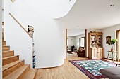 Offener Wohnraum mit Holztreppenaufgang und Durchgang, Blick auf Geschirrschrank