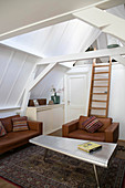 Wohnzimmer mit cognacfarbenen Ledermöbeln und Leiter zu Dachgalerie