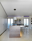 Open-plan kitchen with fitted cupboards below sloping ceiling