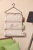 Hand-sewn magazine rack hanging from vintage coat hanger on wall