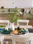 Gedeckter Tisch mit Olivenöl, Oliven, Käse und Brot im Wohnzimmer