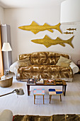 Blanket on sofa below sculptures of fish on wall, coffee table and side tables in living room