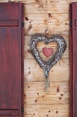 Heart-shaped wreath between window shutters on wooden façade