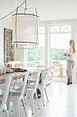 Woman looking out of window in dining room with white floor