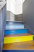 Bunt gestrichene Stufen einer alten Treppe, zweifarbige Wände und Türen