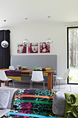 View across sofa with colourful blanket to dining area with grey bench and Mona-Lisa triptych