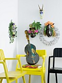 Various ethnic animal masks decorated with flowers above ethnic guitar on yellow armchair