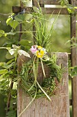 Wreath of grasses, decorated with cow parsley, red campion and buttercups on wooden fence