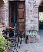 Delicate, folding, metal outdoor furniture outside traditional Mediterranean front door