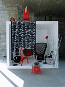 Black and red designer furniture in white cube in front of concrete wall