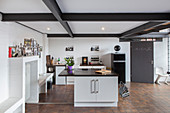 Island counter and brown floor in open-plan industrial-style kitchen