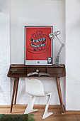 White designer chair at wooden desk with red artwork
