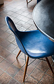 Blue designer chair at round table on brown tiled floor