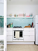 Pale blue tiled splashback and open shelf in bright kitchen