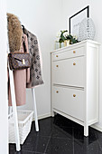 White shoe cabinet with brass knobs and coat rack in hallway