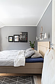 Bed with wooden headboard in bedroom with grey walls