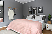 Pink blanket on bed in bedroom with grey walls