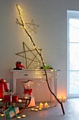 Atmospheric Christmas arrangement: cascade of LED lights on branch, willow star, tealights, candles and gifts