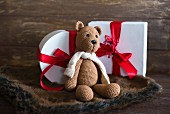 Knitted teddy bear in front of Christmas presents