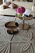 Two round shiny side tables on rug with floral relief pattern