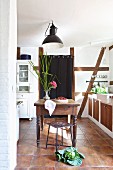 Traditionelle Landhausküche mit Fachwerkwand, Kohlkopf auf Fliesenboden und Holztisch mit Blume