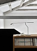 Designer-Schreibtischleuchte auf Zeitschriftenregal neben schwarzer Treppenbrüstung in Loft