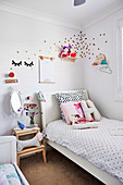 White bed with dotted bed linen, next to it a bedside table with a dog figure in the children's room