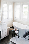 Freestanding bathtub in the bathroom with white shutters