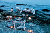 Romantisches Picknick mit Windlichtern, Laternen, Liege und Kissen am Meer