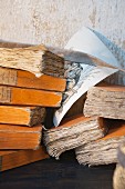 Stack of books with yellowed pages and pen-and-ink drawing against shabby wall
