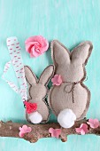 Two fabric rabbits and paper flowers on branch