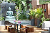 Potted palms, Buddha statue, stools and table on exotic terrace