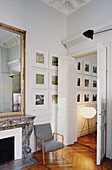 Mirror above fireplace, grey armchair and gallery of pictures next to open double doors
