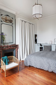Doppelbett mit gepunkteter Bettwäsche, Umkleidekabine mit Vorhang und Kamin im Schlafzimmer