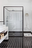 Shower cubicle with glass walls in black and white bathroom