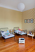 Twin beds in children's bedroom with wallpaper on accent wall in period apartment