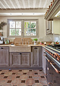 L-shaped country-house kitchen counter with terracotta floor tiles