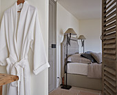 Blick ins Schlafzimmer mit Doppelbett und Stehlampen, im Vordergrund aufgehängter Bademantel