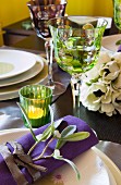 Flower arrangement, tealight and wineglasses on festively set table