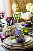 Flower arrangement, tealight and wineglasses on festively set table