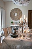 Candelabra on festively set dining table in front of antique mirror on wall
