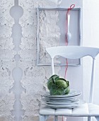 Stacked plates and cabbage on white chair in front of decorated wall