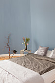 Double bed and side table in bedroom with blue walls