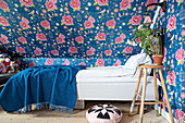 Bed under sloping ceiling covered in floral wallpaper
