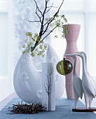 Crane figurines in front of branches and various vases