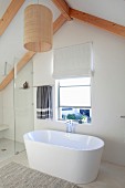 Modernes, helles Bad mit freistehender weißer Badewanne vor Giebelfenster