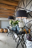 Elegant table lamps on black console table in hallway against black and white wall