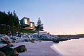 Zwei moderne Strandhäuser in Küstenlandschaft und romantischer Abendstimmung
