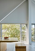 Minimalistischer, hoher Essbereich mit Designer-Holzmöbeln vor Terrassentür