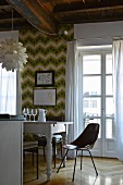 Chair and white dining table in front of retro wallpaper and French window in renovated period apartment